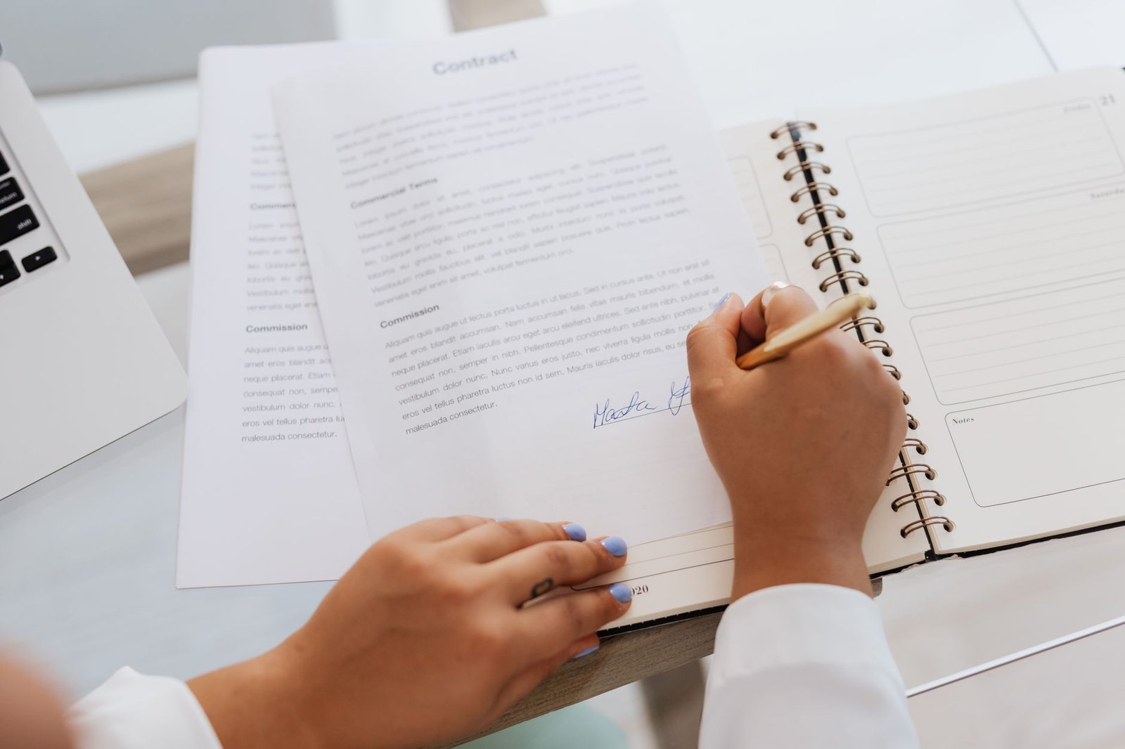 Hands signing a document on a desk with office supplies