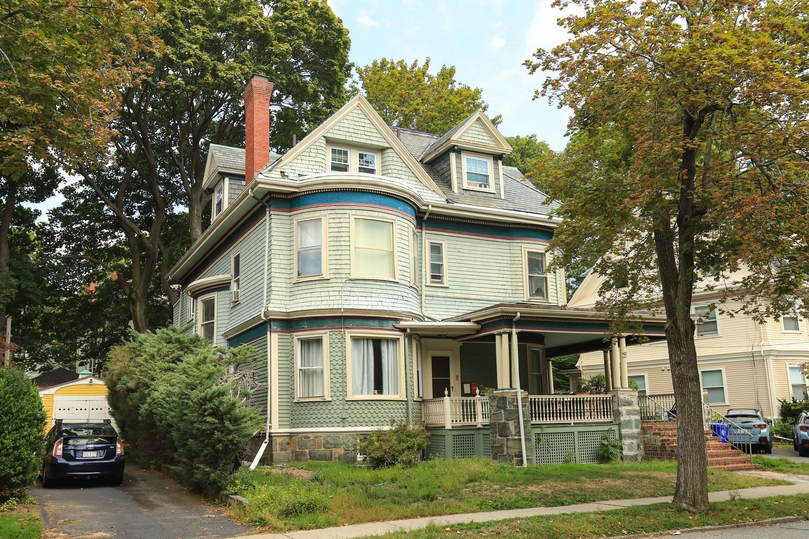 Victorian-style house with a covered porch surrounded by trees